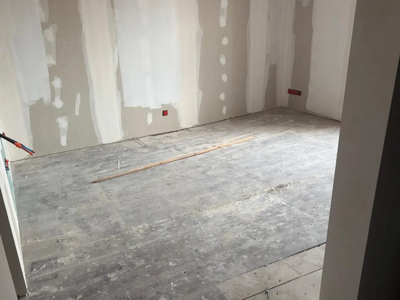 Avant : pièce au plancher ancien usé, murs en plaques de plâtre aux bandes