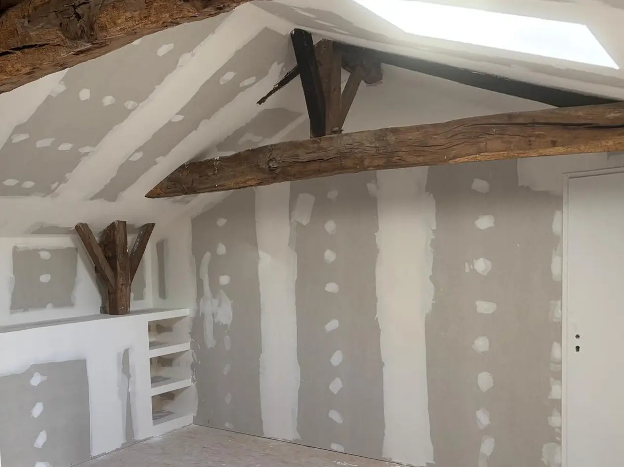 Avant : pièce mansardée aux bandes, meuble bas et étagères en plaques de plâtre, poutre et ferme anciennes, porte