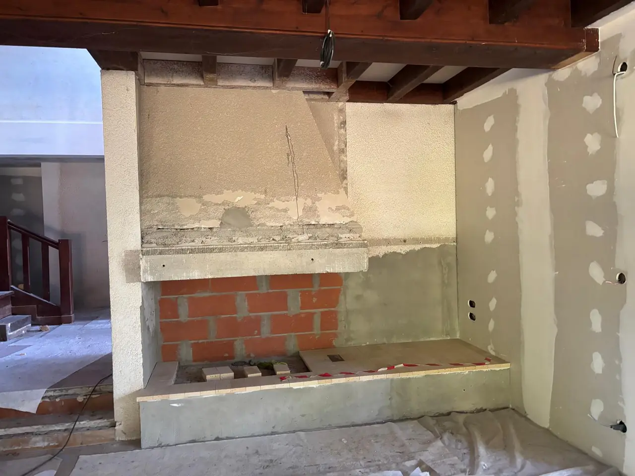 Ancienne cheminée avant habillage, hotte enduite, contrecœur en briques, plafond à poutres