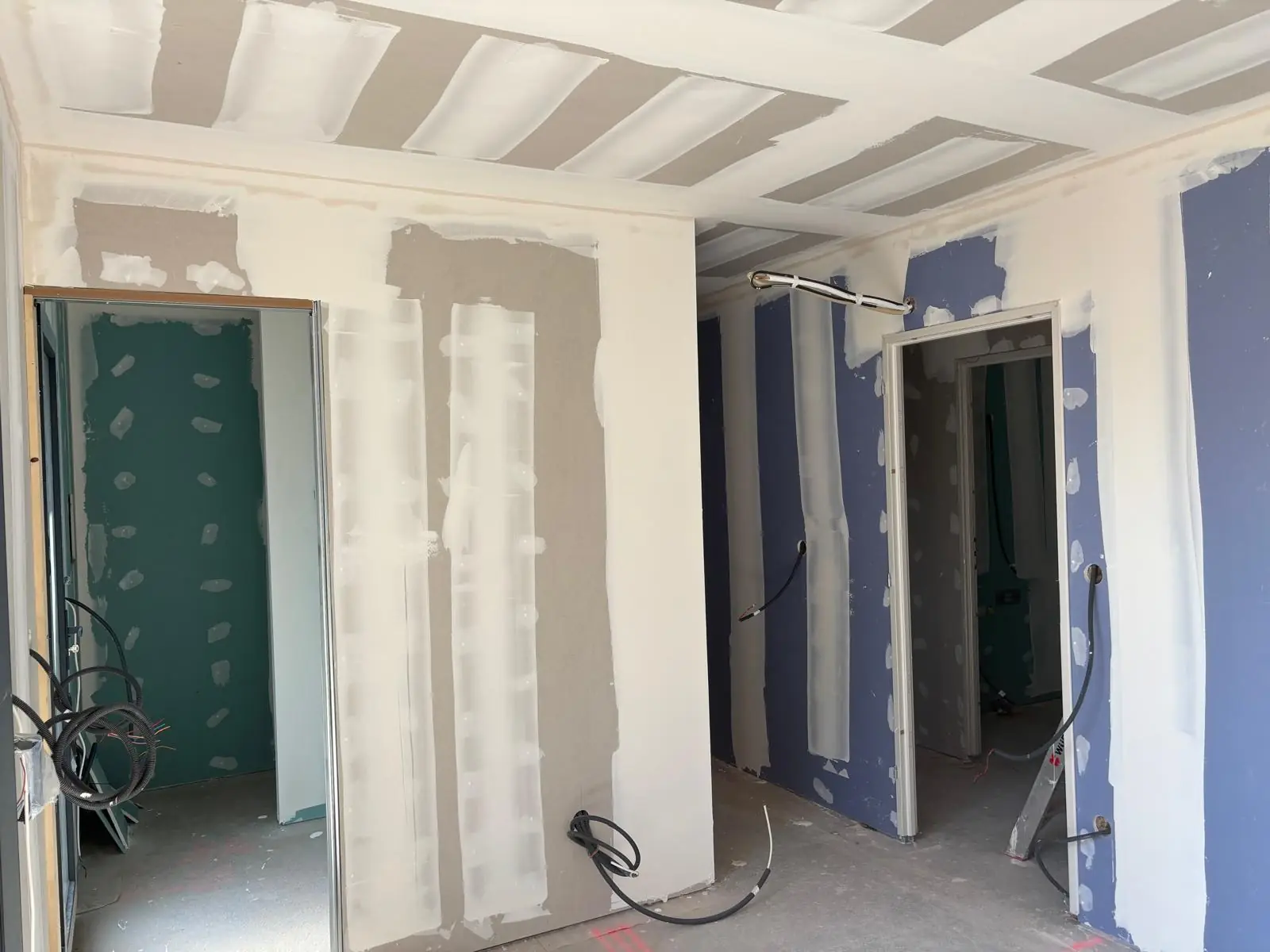 Cloisons en plaques de plâtre aux bandes avec deux passages de porte, plaques hydrofuges vertes dans la pièce de gauche