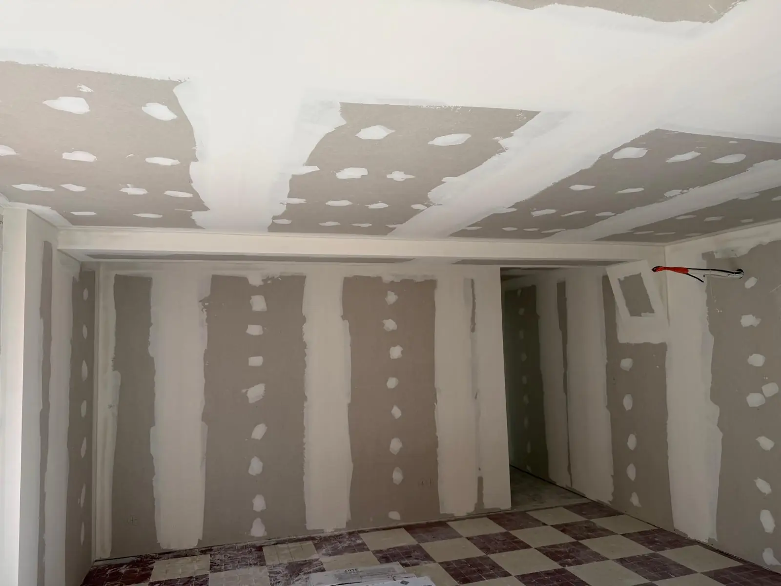 Pièce doublée et plafonnée en plaques de plâtre, bandes faites, sol en carrelage damier d’origine