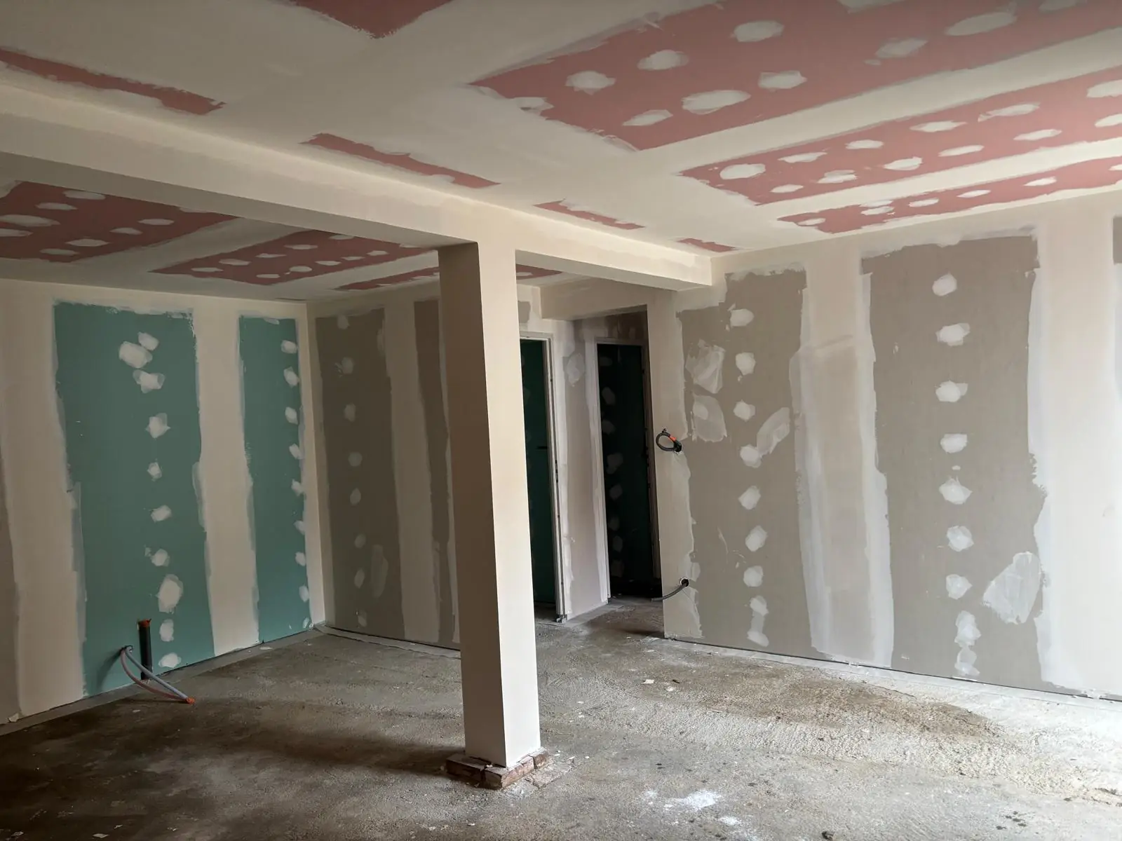 Pièce au plafond en plaques de plâtre et aux murs doublés, bandes faites, poteau habillé, plaques hydrofuges vertes