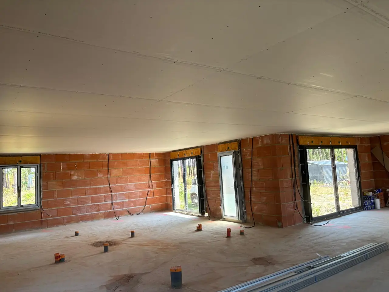 Plafond en plaques posé dans une maison neuve, murs en briques avec gaines électriques en attente